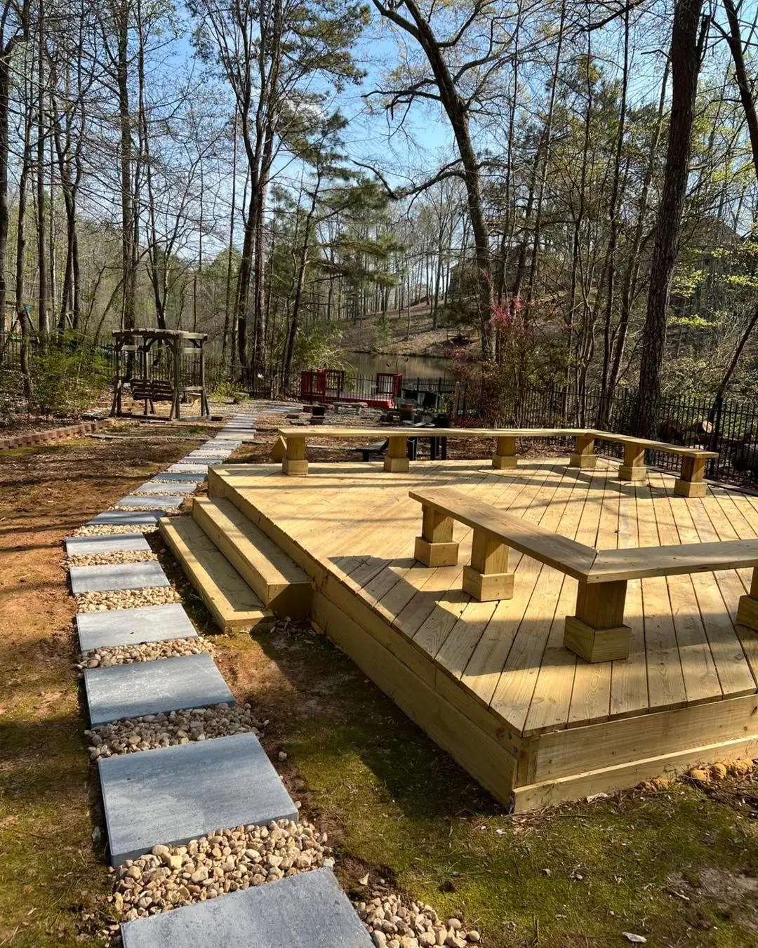 Low ground-level wood deck with built-in benches and a stepping-stone path