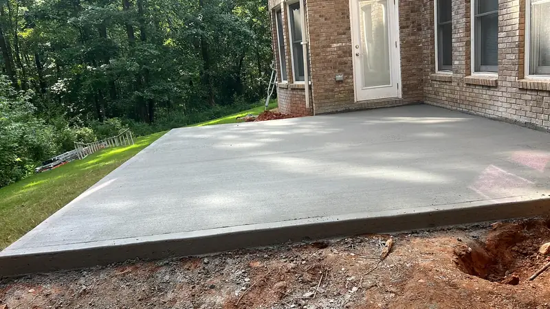 Fresh concrete patio slab behind a brick house