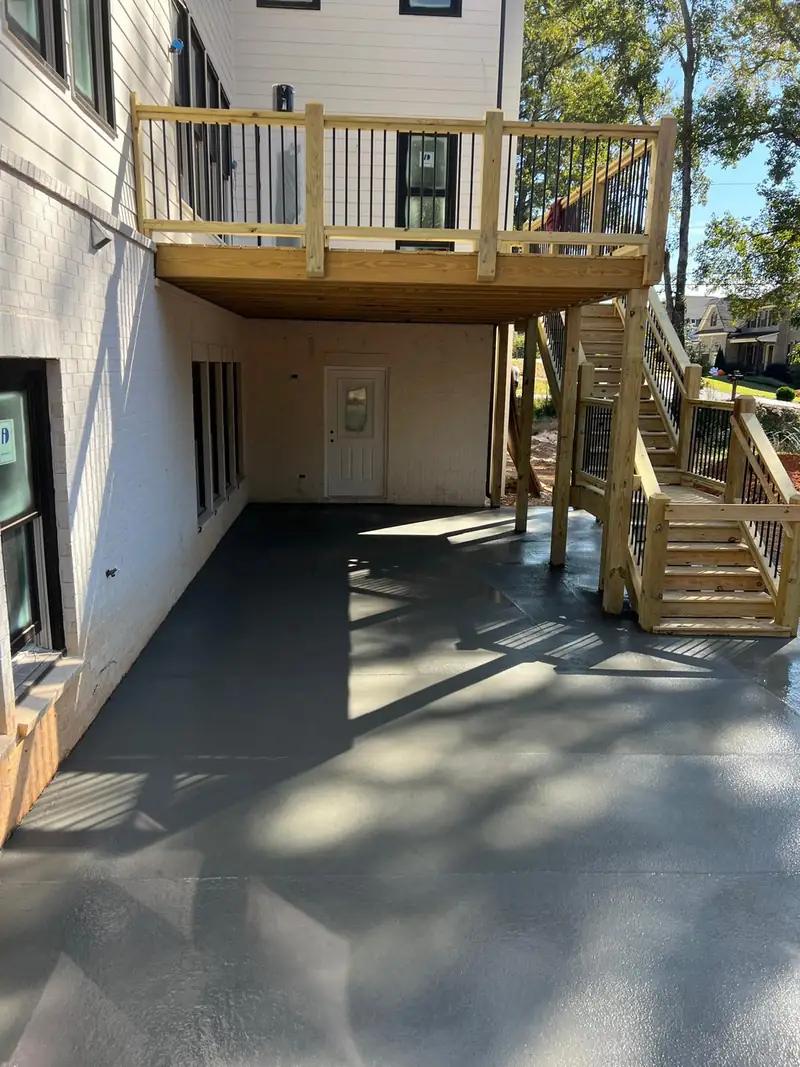 Concrete patio slab under a two-story wood deck and stairs