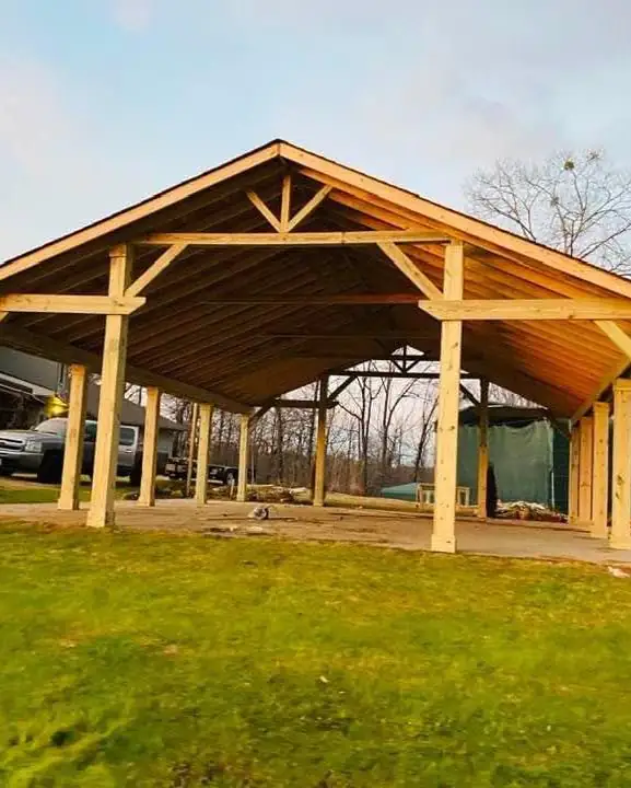 Large timber pavilion with king-post trusses over a concrete slab