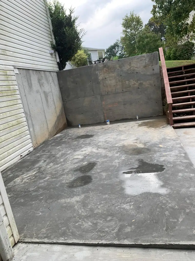 Poured concrete retaining wall beside a new slab and stairs