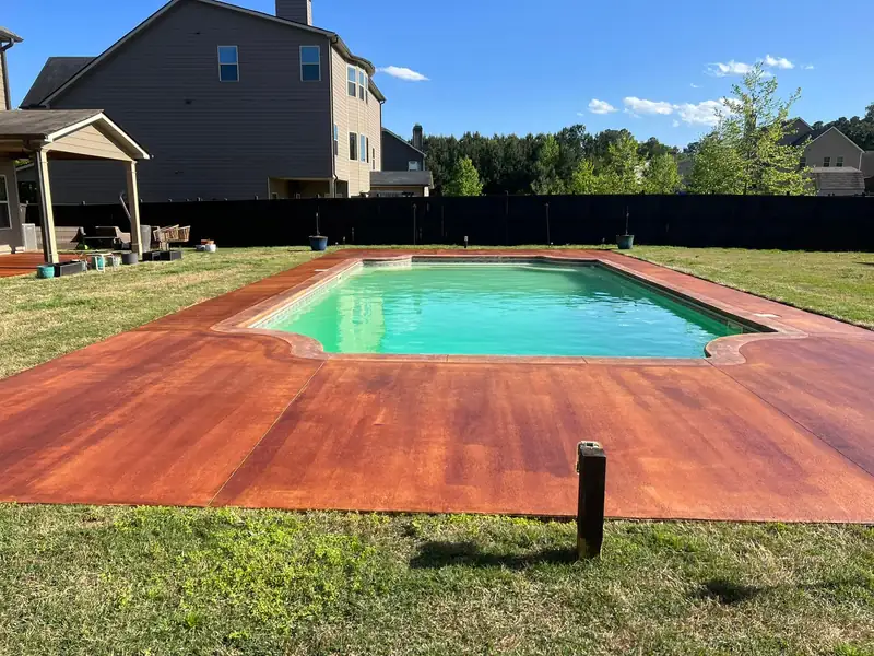 Stained concrete pool deck in a fenced backyard