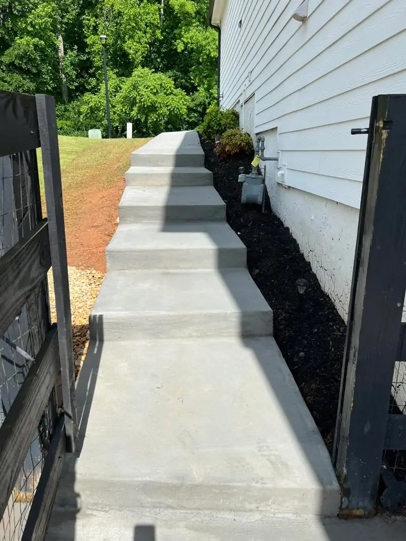 Concrete side-yard steps and walkway along white siding and a fence